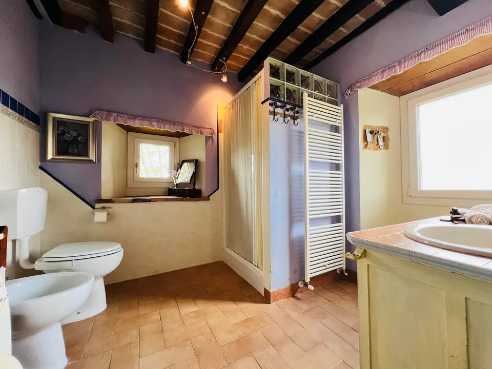 Bagno rustico di Casa Vedetta con travi a vista, sanitari bianchi e bidet