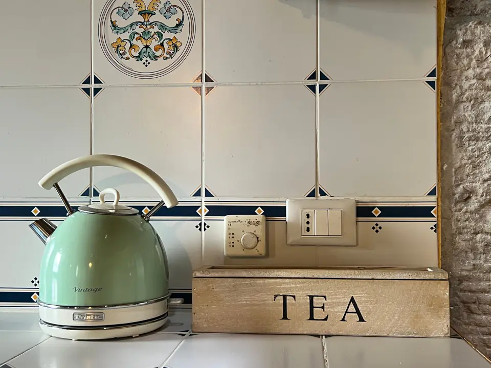 Bollitore verde vintage e bustine di tè sul piano della cucina di Casa Vedetta