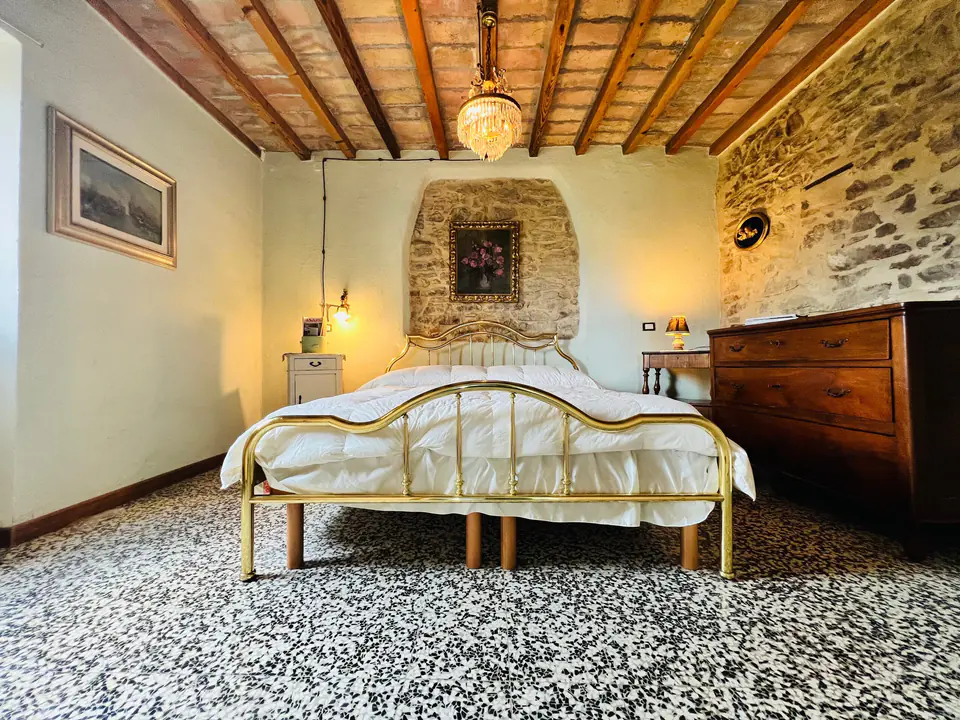 Camera da letto matrimoniale di Casa Vedetta con armadio in legno antico e soffitto in travi