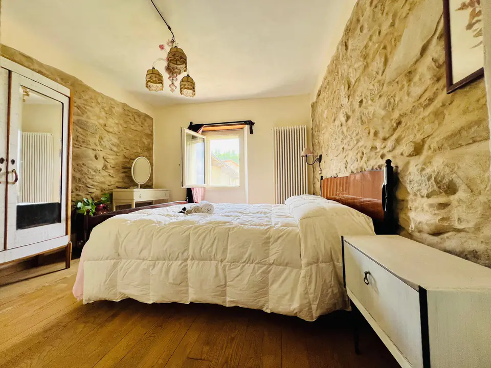 Camera matrimoniale di Casa Vedetta con parete in pietra a vista e finestra sul verde