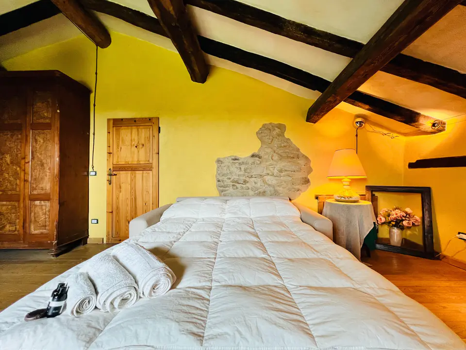 Camera da letto sottotetto di Casa Vedetta con capriate in legno a vista