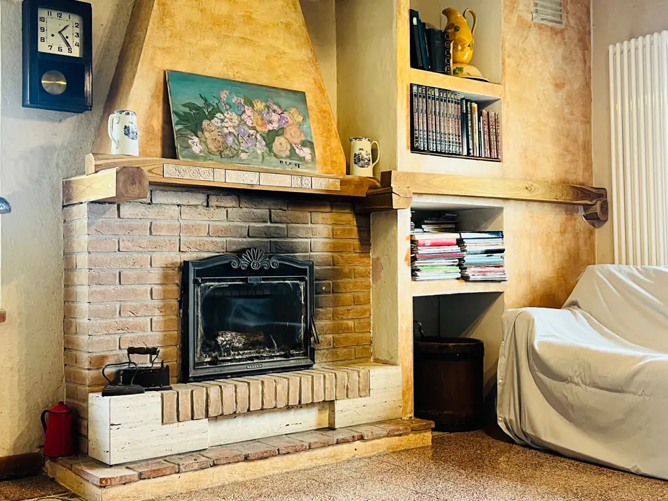 Camino in mattoni nella sala relax di Casa Vedetta con libreria e divano