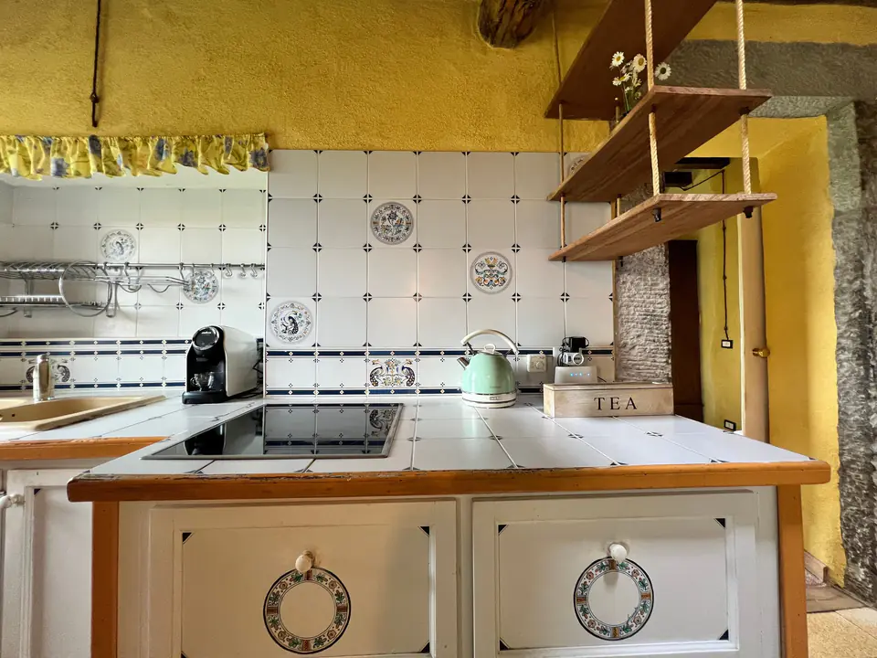Cucina completa di Casa Vedetta con piano cottura, macchina del caffè e mensole in legno