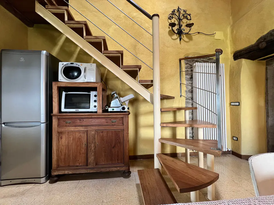 Angolo cottura di Casa Vedetta con frigorifero, forno a microonde e scala a chiocciola