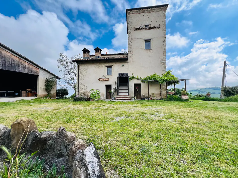 La torre e il corpo principale di Casa Vedetta visti dal prato in una giornata di sole
