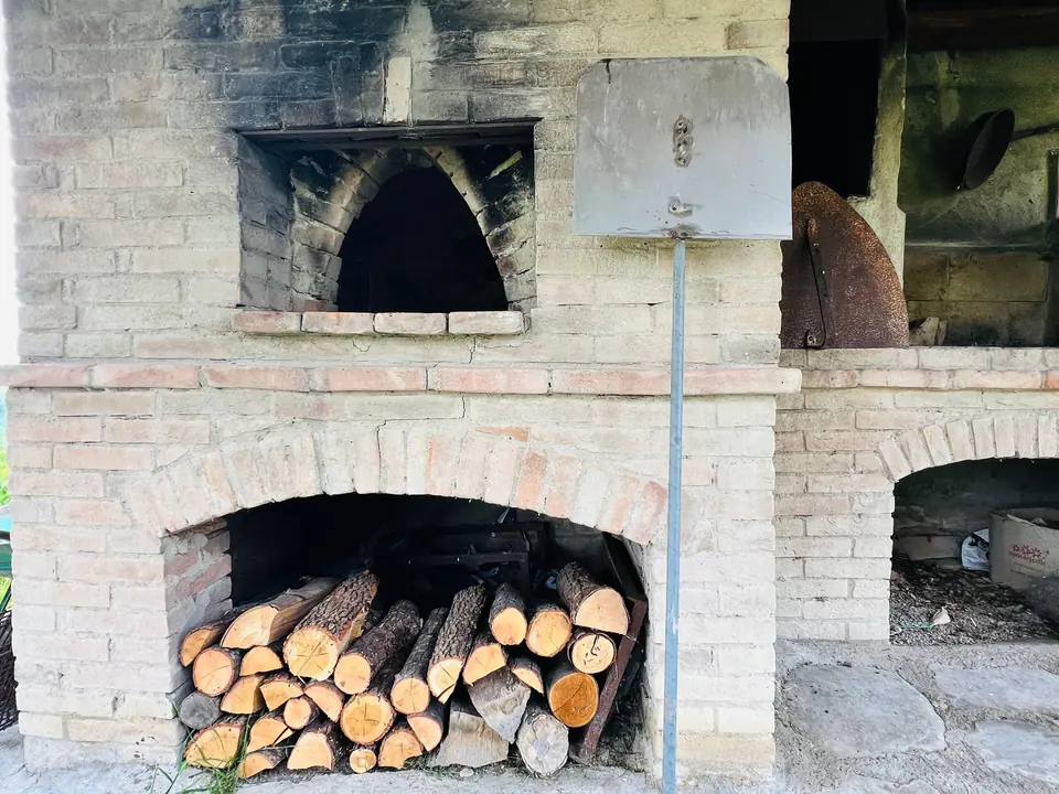 Forno a legna in mattoni con la legna accatastata, pronto per la pizza, a Casa Vedetta