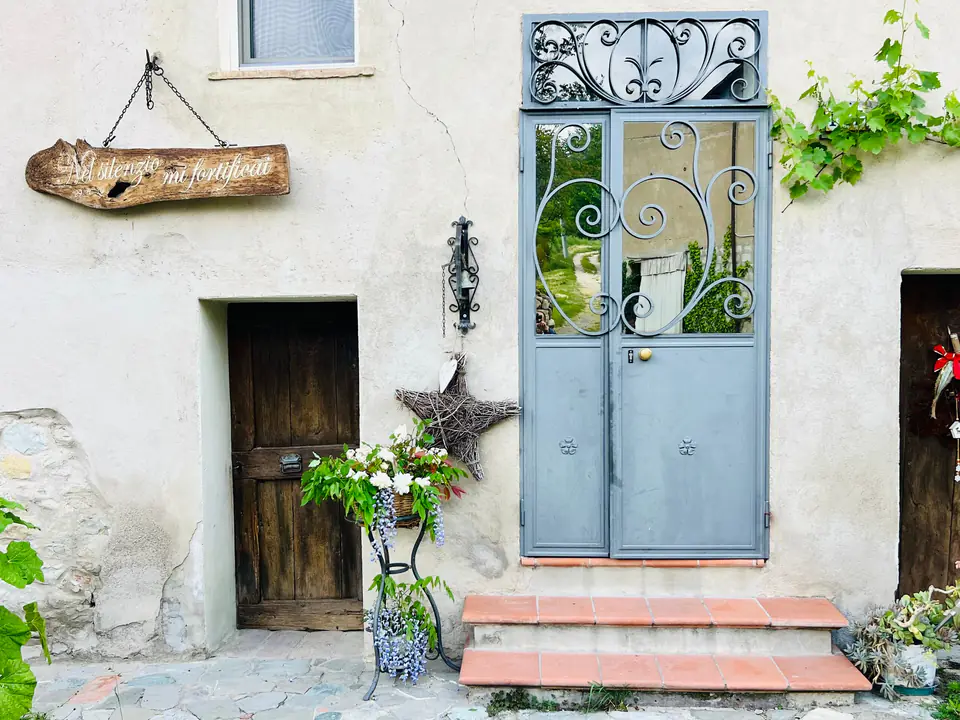 Ingresso di Casa Vedetta con porta azzurra, gradini in cotto e vasi di fiori