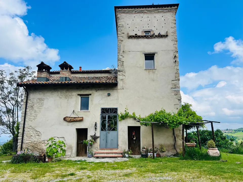 La torre di avvistamento di Casa Vedetta si staglia contro il cielo azzurro sulle colline di Montecorone