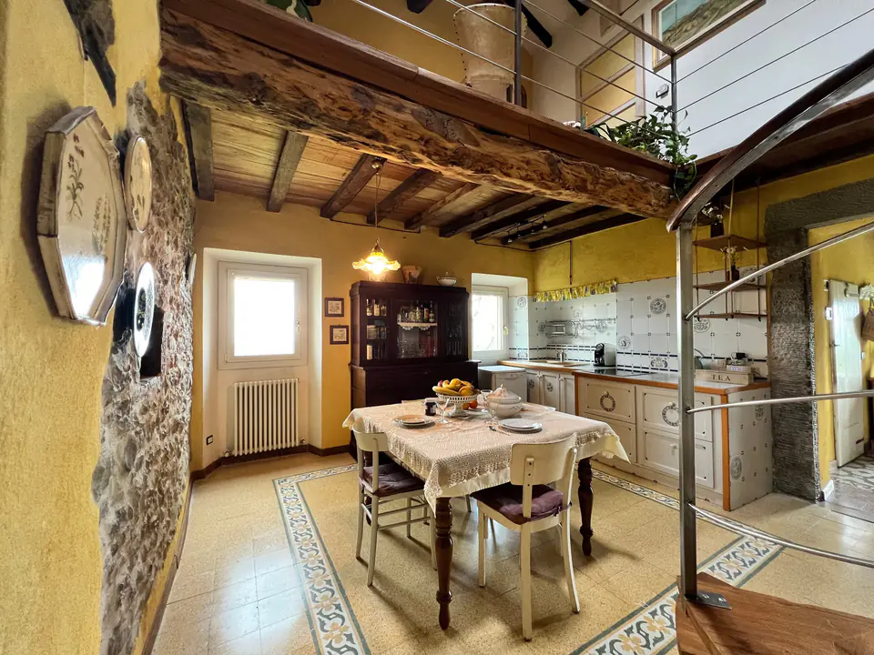 Sala da pranzo di Casa Vedetta con tavolo in legno, travi a vista e muri in pietra