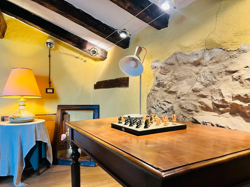 Scacchiera vintage su un tavolo in legno davanti a una parete in pietra a Casa Vedetta