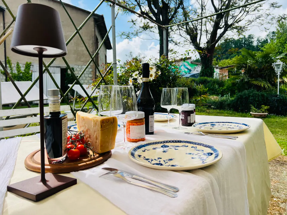Tavola apparecchiata all’aperto con calici di vino e taglieri nel giardino di Casa Vedetta