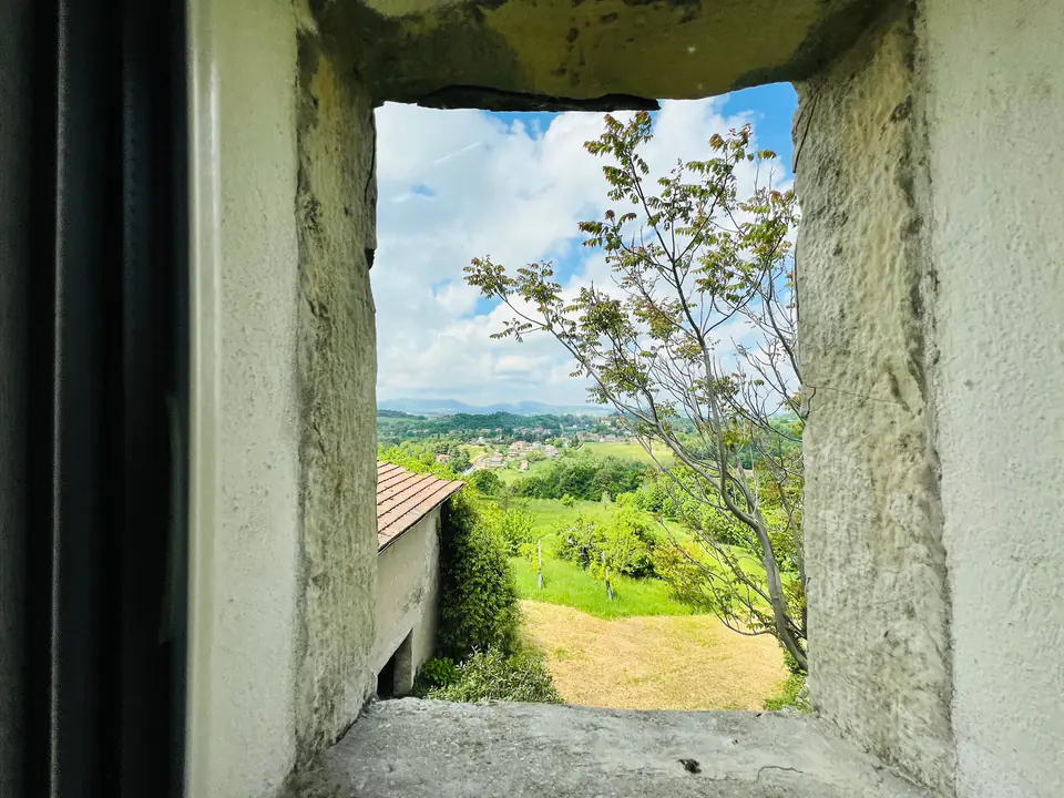 Vista sulle colline verdi attraverso una finestra scavata nel muro in pietra di Casa Vedetta